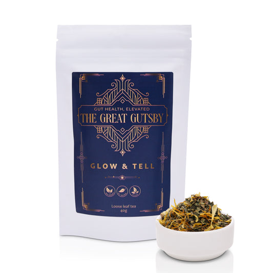Glow & Tell detox and skin radiance tea blend with herbal ingredients for gut health support, presented in premium Art Deco navy and gold packaging.